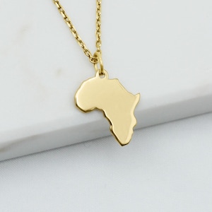 Peut inclure: Un collier doré composé d'une chaîne fine et d'un pendentif plat et poli en forme du continent africain. Le pendentif est suspendu à un petit anneau de jonction fixé à la chaîne, formant un bijou au design simple et épuré.