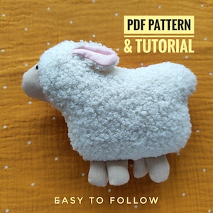 May include: A plush white sheep toy with pink ears and beige legs rests on a yellow dotted surface. The text "PDF PATTERN & TUTORIAL" and "EASY TO FOLLOW" are displayed in the image, indicating a craft project.