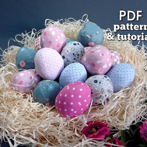 Könnte beinhalten: Eine Ansammlung von Stoff-Ostereiern in einem Strohnest. Die Eier sind in verschiedenen Farben gehalten, darunter Rosa, Blau und Weiß, mit Tupfen und floralen Mustern. Der Text "PDF pattern & tutorial" ist sichtbar.