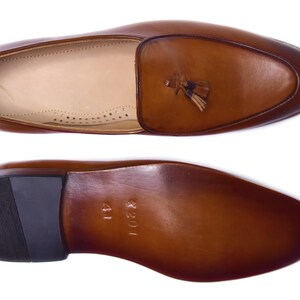 May include: Brown leather tassel loafers with a black rubber sole. The sole is marked with "1201" and "41".