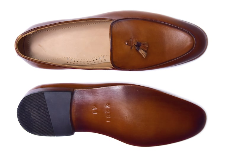 May include: Brown leather tassel loafers with a black rubber sole. The sole is marked with "1201" and "41".