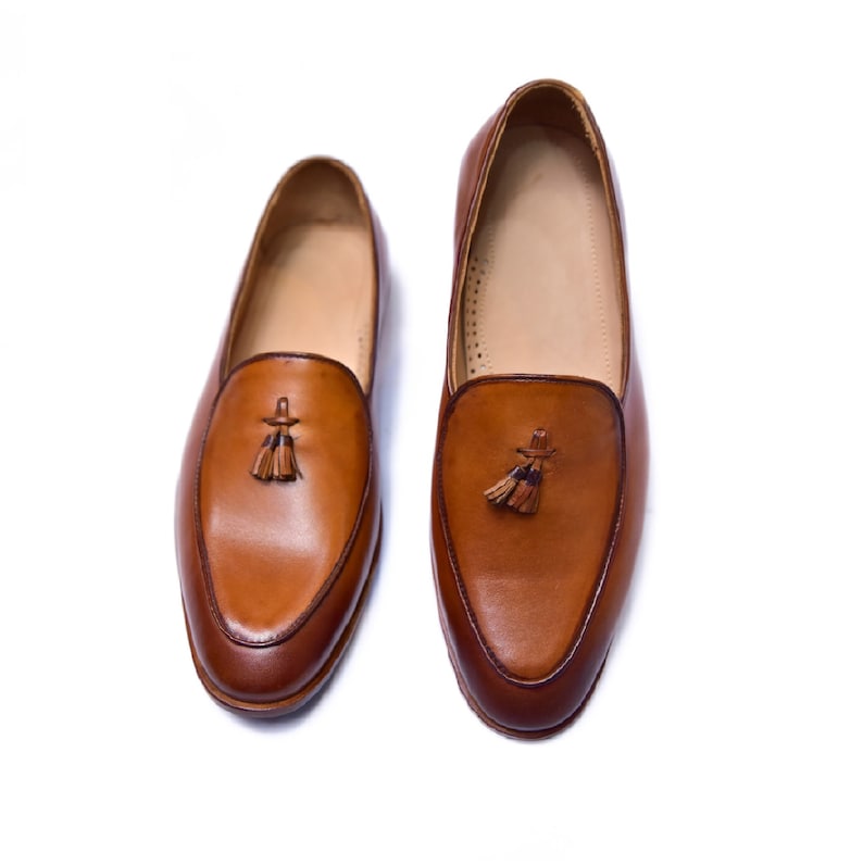May include: A pair of brown leather loafers with tassels. The loafers have a pointed toe and a slip-on design.