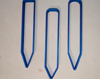 May include: Three blue, pencil-shaped cookie cutters of varying sizes. Each cutter has a pointed tip and a rounded or squared top, creating a simple, clean design. The cutters are made of a solid, opaque material.