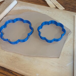 Pottery clay cutter in the shape of a circle with scalloped edges. There is an example project of a flower shaped trinket dish made from the cutter.