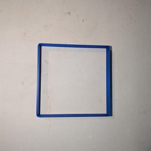 May include: A square, white canvas with a bright blue frame. The frame is a solid, vibrant blue, creating a defined border around the canvas. The canvas is centered, and the background is a neutral, off-white color.