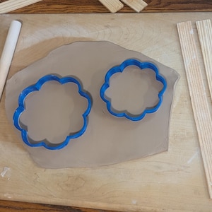 Pottery clay cutter in the shape of a circle with scalloped edges. There is an example project of a flower shaped trinket dish made from the cutter.
