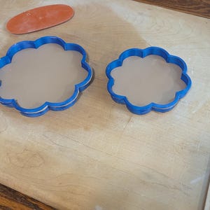 Pottery clay cutter in the shape of a circle with scalloped edges. There is an example project of a flower shaped trinket dish made from the cutter.