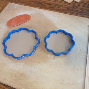 Pottery clay cutter in the shape of a circle with scalloped edges. There is an example project of a flower shaped trinket dish made from the cutter.