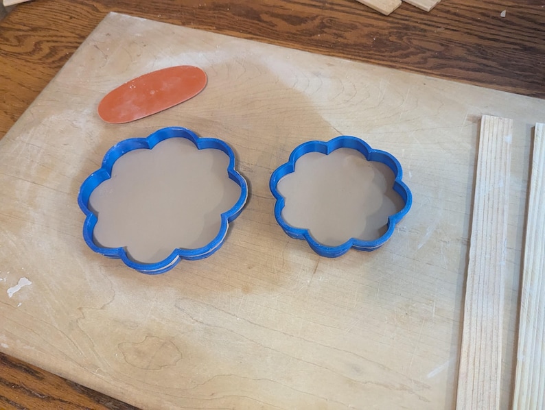 Pottery clay cutter in the shape of a circle with scalloped edges. There is an example project of a flower shaped trinket dish made from the cutter.