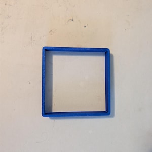 May include: A bright blue square-shaped cookie cutter. The cutter is made of plastic and has a simple, clean design. The square shape is perfect for creating uniform cookies or other baked goods.