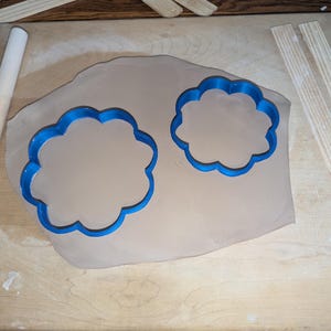 Pottery clay cutter in the shape of a circle with scalloped edges. There is an example project of a flower shaped trinket dish made from the cutter.