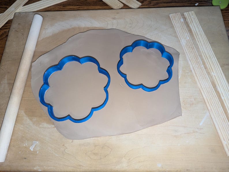 Pottery clay cutter in the shape of a circle with scalloped edges. There is an example project of a flower shaped trinket dish made from the cutter.