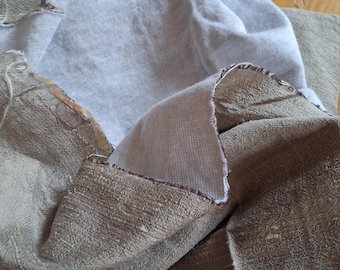 May include: Close-up of fabric remnants. The image shows two pieces of fabric, one a light gray knit and the other a textured olive green. The edges of the fabric are raw and unfinished, with visible threads. The fabrics are layered and folded.