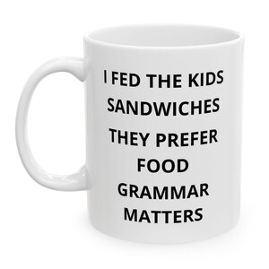 May include: White ceramic mug with the text "I FED THE KIDS SANDWICHES THEY PREFER FOOD GRAMMAR MATTERS" in black, centered on the mug. The mug has a white handle and a white interior. The mug is on a white background.