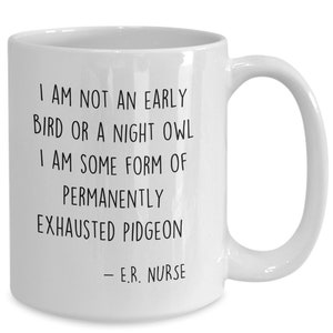 May include: White ceramic coffee mug with black text that reads "I am not an early bird or a night owl. I am some form of permanently exhausted pigeon - E.R. Nurse."