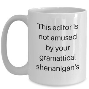 Może przedstawiać: Biały ceramiczny kubek do kawy z czarnym tekstem, kt&oacute;ry brzmi "This editor is not amused by your grammatical shenanigans".