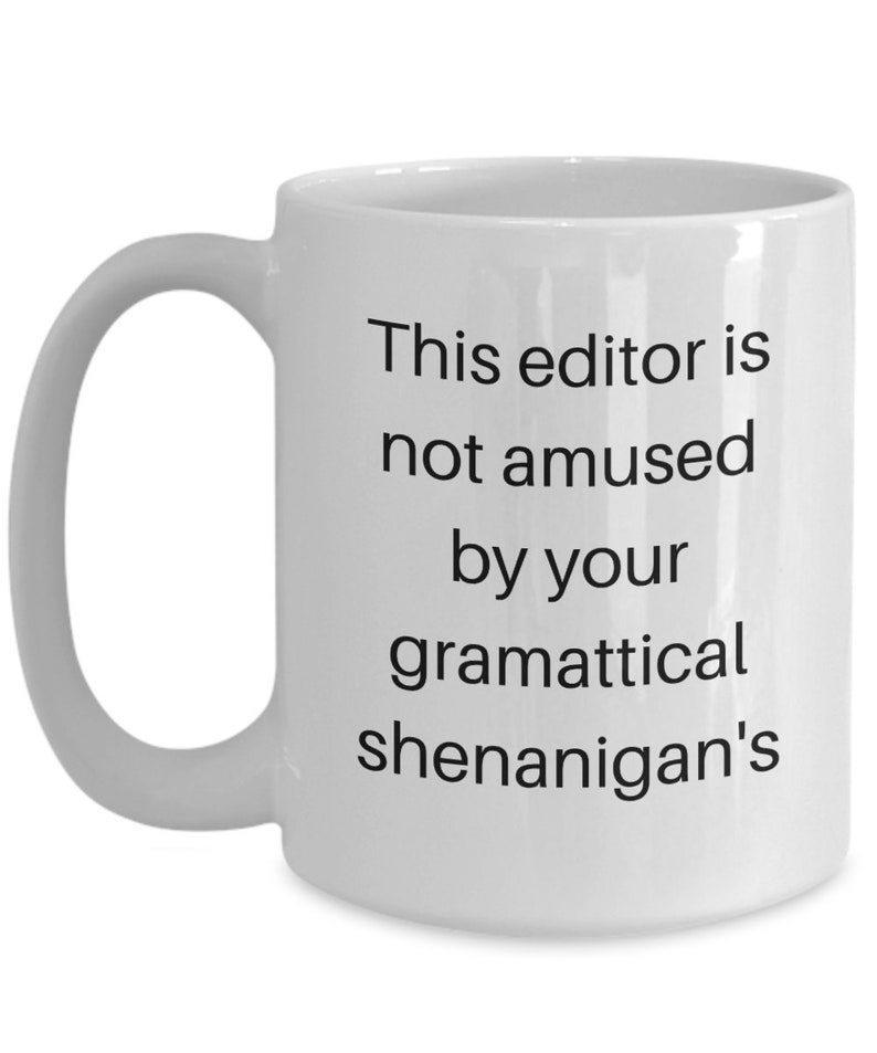 Może przedstawiać: Biały ceramiczny kubek do kawy z czarnym tekstem, kt&oacute;ry brzmi "This editor is not amused by your grammatical shenanigans".