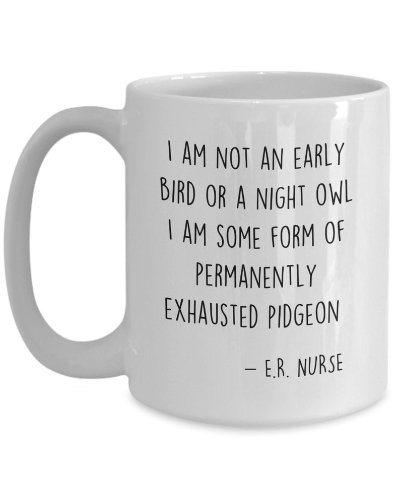 May include: White ceramic coffee mug with black text that reads: "I am not an early bird or a night owl. I am some form of permanently exhausted pigeon - E.R. Nurse"