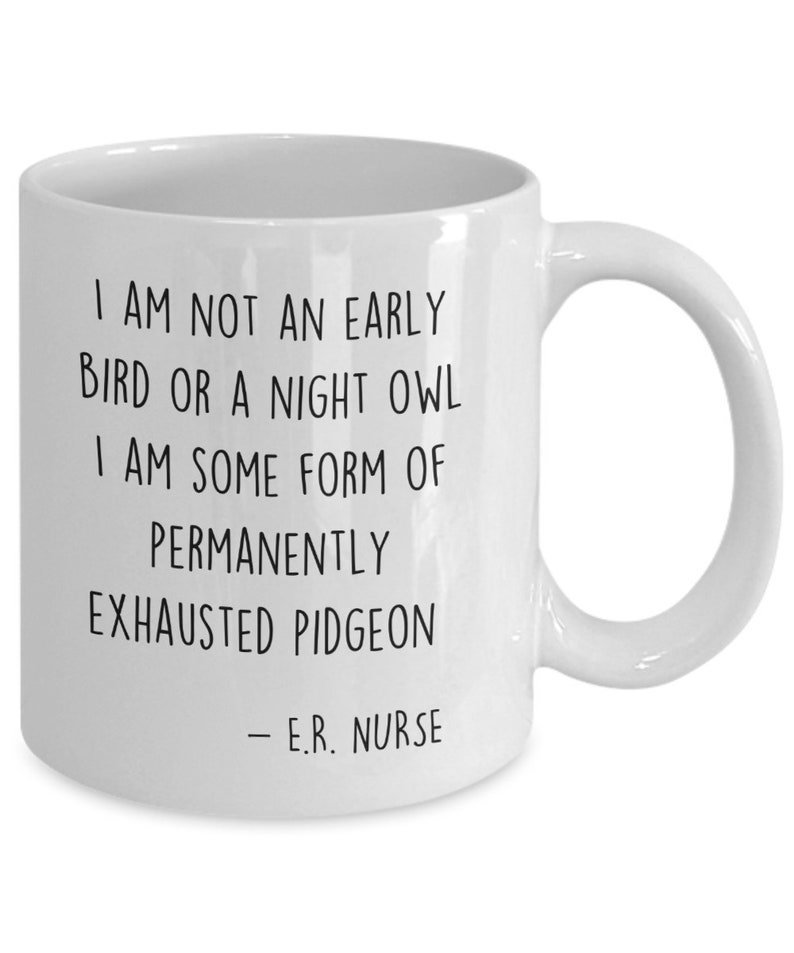 May include: White ceramic coffee mug with black text that reads "I am not an early bird or a night owl. I am some form of permanently exhausted pigeon - E.R. Nurse."