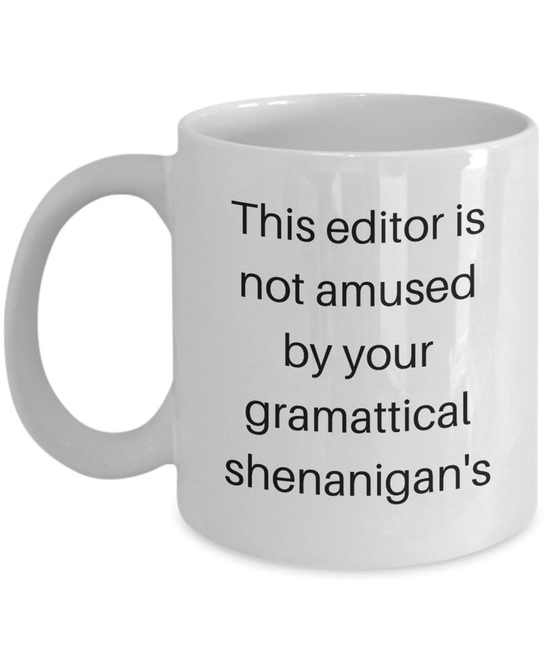 Może przedstawiać: Biały ceramiczny kubek do kawy z czarnym tekstem, kt&oacute;ry brzmi "This editor is not amused by your grammatical shenanigans".
