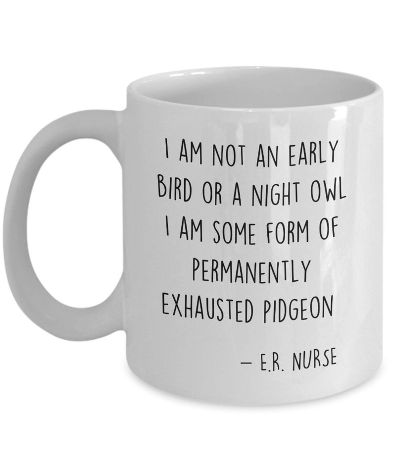May include: White ceramic coffee mug with black text that reads: "I am not an early bird or a night owl. I am some form of permanently exhausted pigeon - E.R. Nurse."