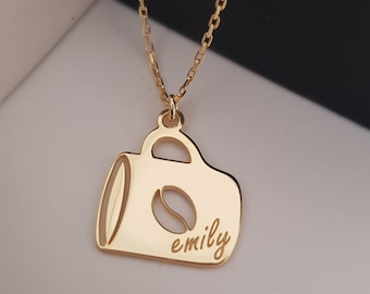 May include: Gold necklace with a coffee cup pendant. The pendant has a coffee bean cutout and the name "emily" engraved on it.