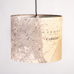 May include: A beige lampshade featuring a vintage map of Cardiff, Wales. The map shows the "East Division" and the text "CARDIFF" in large, bold letters.