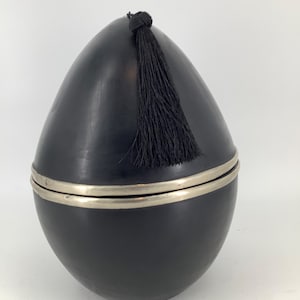 Può includere: Contenitore in ceramica nero a forma di uovo con un bordo in metallo argentato e un fiocco nero.