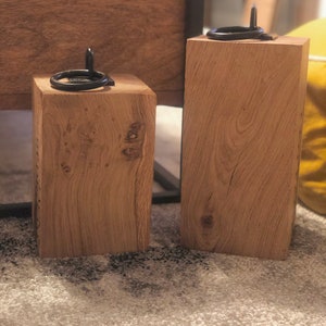 K&ouml;nnte beinhalten: Zwei Holzt&uuml;rstopper mit schwarzen Metallringen. Die T&uuml;rstopper sind aus Naturholz in hellbrauner Farbe.