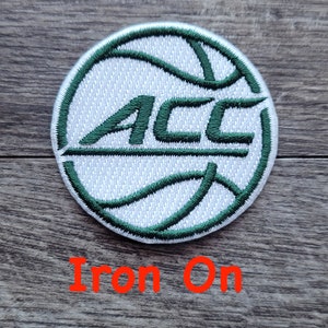 May include: White and green iron-on patch with a basketball design and the letters "ACC" in green.