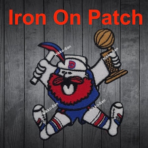 May include: Iron-on patch featuring a cartoon mascot holding a basketball trophy and a pickaxe. The mascot is wearing a blue and red jersey with a white hat and white pants. The patch has a white background with the text "Nikko-San" printed on it.