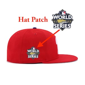 May include: Red baseball cap with a World Series patch on the front. The patch is a diamond shape with a baseball logo and the text "World Series 2022".