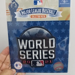 May include: A Major League Baseball collector patch featuring the words "World Series 2021". The patch is navy blue with white lettering and a baseball graphic. The packaging includes the MLB logo and the words "Collector Patch".