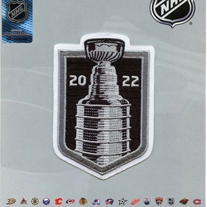 May include: An authentic collectible emblem featuring the NHL logo and the Stanley Cup. The patch is black, white, and gray, with the year 2022 prominently displayed. The official licensed product has a BB123990960 serial number.
