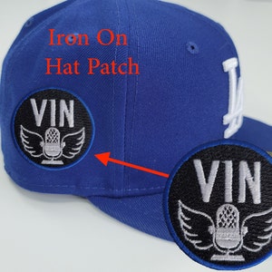 May include: A blue baseball cap with a black and white iron-on patch that says "VIN" with a microphone and wings. The text "Iron On Hat Patch" is written in red above the patch.