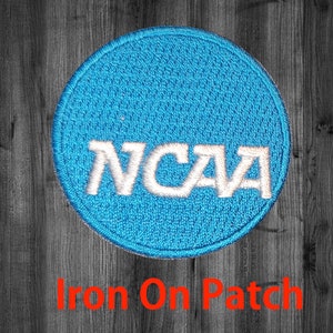 May include: A blue and white iron-on patch with the NCAA logo. The patch is circular and has a textured fabric surface.