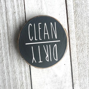 May include: A black round wooden sign with white text that reads "CLEAN DIRTY".