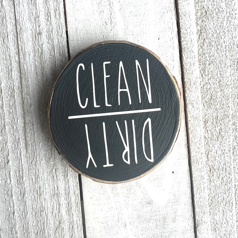 May include: A black round wooden sign with white text that reads "CLEAN DIRTY".