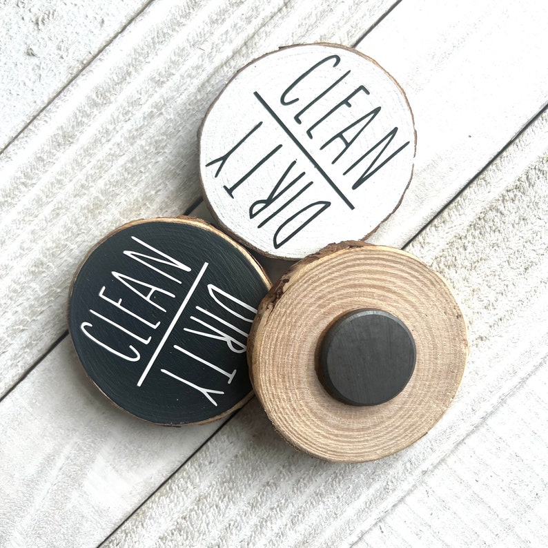 May include: Two round wooden signs with the words "Clean" and "Dirty" written on them. The signs are black and white and have a rustic look. The signs are attached to a round wooden magnet.