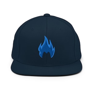 Peut inclure: Casquette de baseball bleu marine avec une visière plate. Le chapeau présente un motif de flamme bleue brodée sur le devant. Il a une coupe structurée et une fermeture à pression.