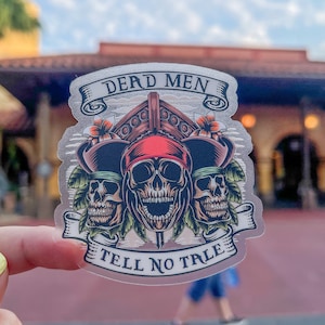 Puede incluir: Una pegatina transparente con un diseño de calavera y huesos cruzados. La calavera lleva un pañuelo rojo y un sombrero negro. El texto "Dead Men Tell No Tales" está escrito en una pancarta debajo de la calavera.