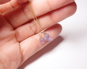 May include: A pair of delicate gold chain earrings with purple agate stone drops. The earrings are shown on a hand against a white background.