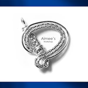 May include: A silver wire pendant with a looped design. The pendant has detailed wire wrapping and the text "Aimee's Workshop". It is suspended from a small loop at the top.