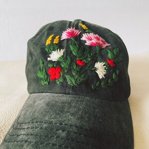 May include: A dark grey baseball cap with embroidered flowers in shades of pink, red, white, and yellow.