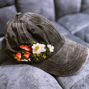 May include: A black baseball cap with embroidered white and orange flowers.
