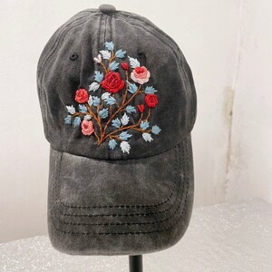May include: A black denim baseball cap with an embroidered floral design featuring red, pink, and blue flowers.