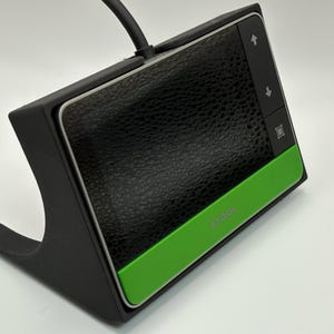 May include: Black and green XTOOL device with a textured surface and control buttons. The device has a black base and a green accent. The XTOOL logo is visible on the green accent.