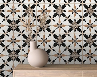 May include: A wooden dresser with two drawers against a wall with a black and brown floral tile pattern. A vase with dried flowers sits on top of the dresser.