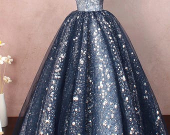Op de afbeelding: Een marineblauwe off-shoulder baljurk met zilveren pailletten. De jurk heeft een getailleerd lijfje en een volle rok. De rok is gemaakt van tule en is versierd met zilveren pailletten. De jurk is perfect voor een formele gelegenheid.