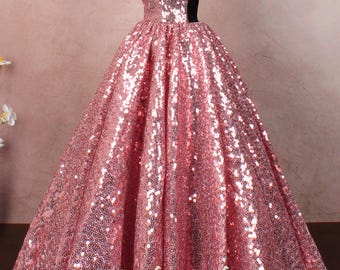Op de afbeelding: Een roze, off-shoulder, paillettenjurk met een zwart fluwelen lijfje. De jurk heeft een volle rok en is perfect voor een formele gelegenheid.